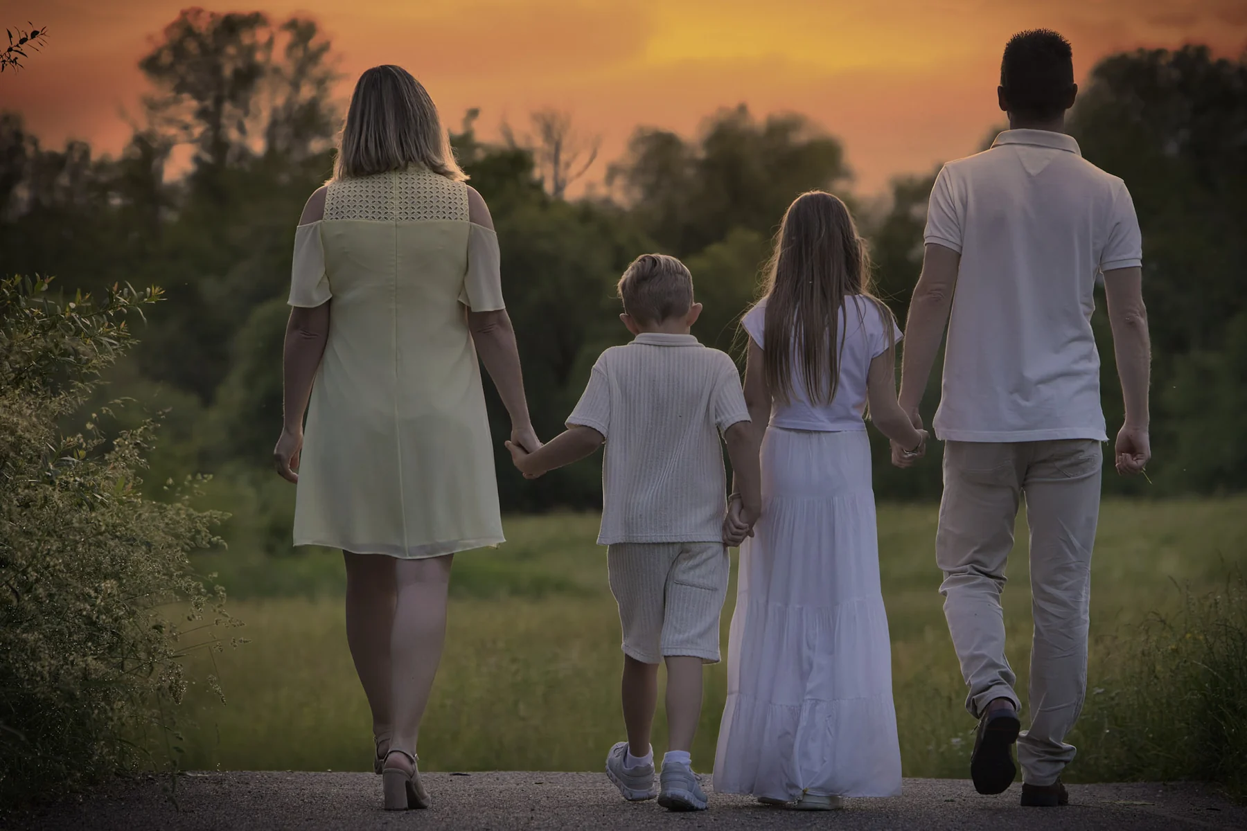 Familie geht bei Sonnenuntergang gemeinsam einen Weg entlang